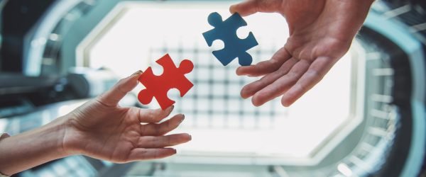 Close-up of business people wanting to put two pieces of puzzle together.